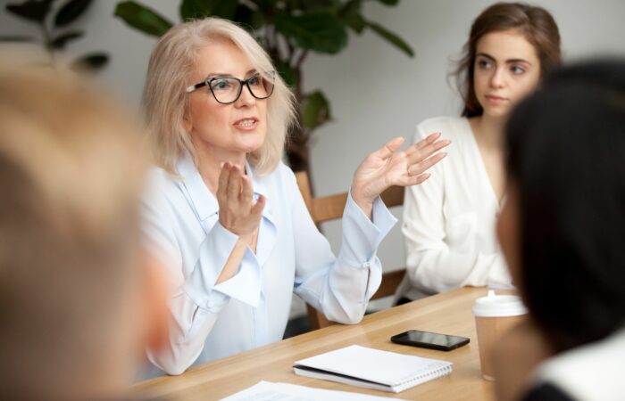 Woman presenting to a group of professionals at a conference table