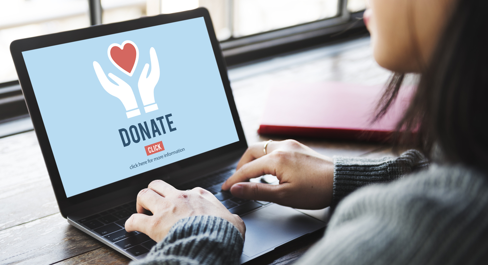 A woman working on a laptop with a Donate image on screen