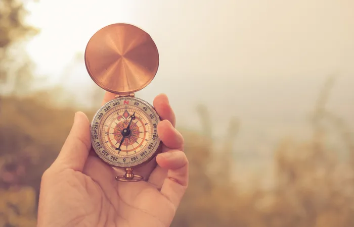 Hand holding a compass pointing north-east